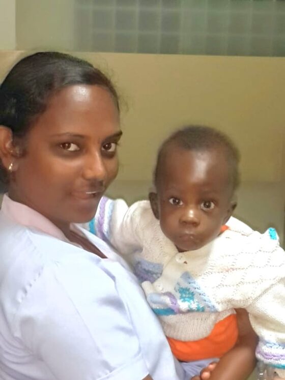 A nurse holds a young patient on the ward.